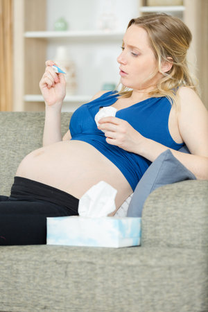 pregnant woman looking at thermometer