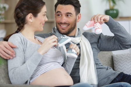 couple expecting baby playing with baby shoes