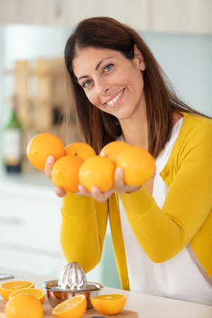 dark-haired woman holding juicy delicious orangesの写真素材