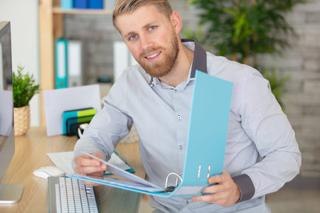 handsome man working with papers and computer at office