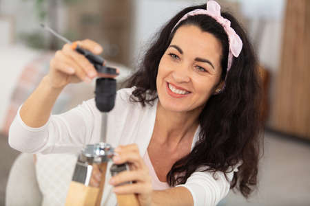 mature woman assembling a lamp in her homeの写真素材