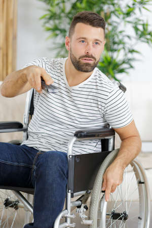 young handsome man in wheelchair watching tvの写真素材