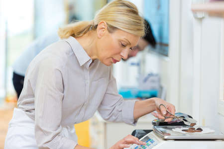 mature shop assistant using electronic scalesの写真素材