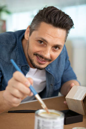diy man painting small wood box at homeの写真素材
