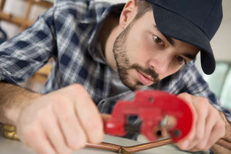 man is cutting cooper pipesの写真素材