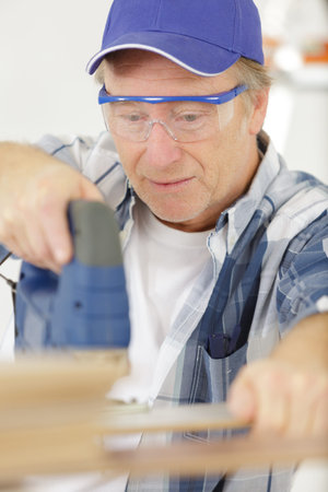 concentrated senior male carpenter cutting wood
