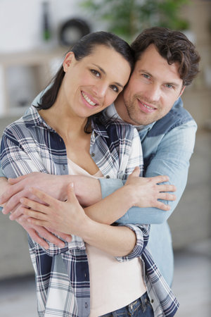 man hug his girlfriend standing at home