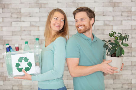 ecological couple hold a plastic container and a small treeの写真素材