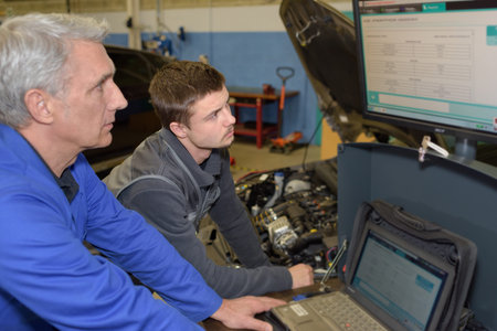 student with instructor repairing a car during apprenticeship