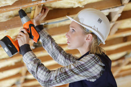 portait of a female worker drilling ceilingの写真素材