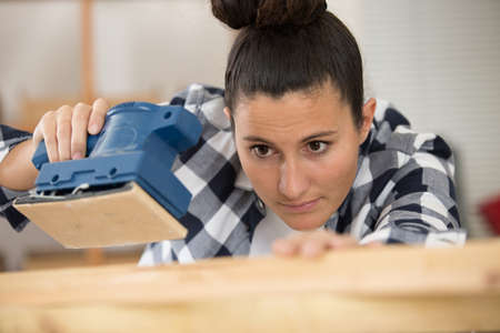 woman using electrical sander on carpentry projectの写真素材