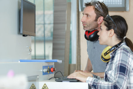 engineer and female apprentice working on machinery in factory