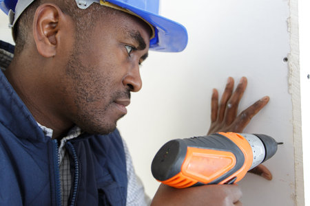 workman makes hole in wall with a drill