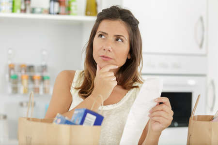 shocked woman holding shopping bill receiptの写真素材