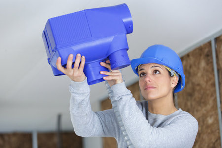 young female worker installing plastic ventilation unitの写真素材