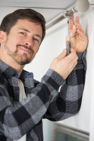 man screwing window curtain rod support on the wallの写真素材