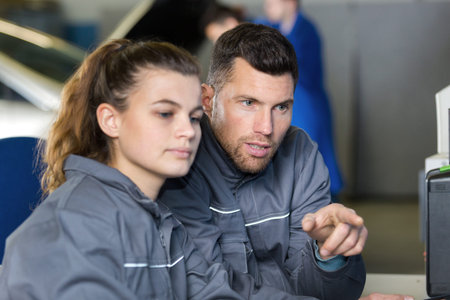 mechanic and apprentice working on computerの写真素材
