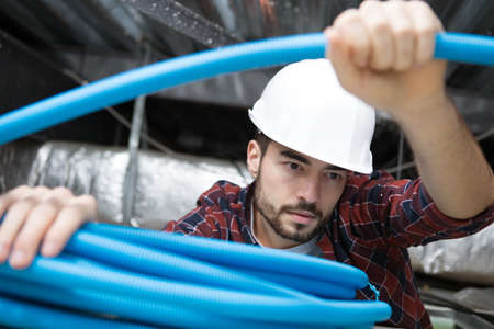 electrical worker wiring in ceilingの写真素材