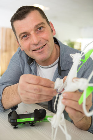 happy man smiling at camera while fixing a crashed drone