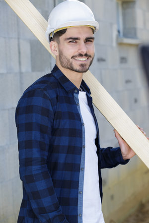 happy young man as builder carrying wood and working