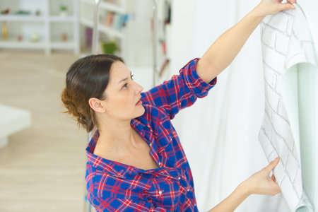 woman holding roll of wallpaper against wall