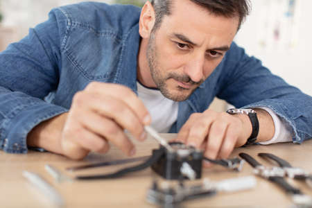 patient man repairing a watch at homeの写真素材