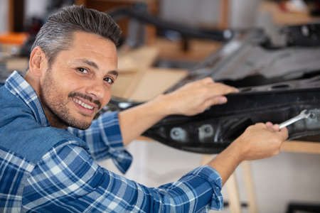 mechanic using spanner on car doorの写真素材