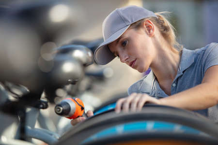 cheerful woman repairing a bicycleの写真素材