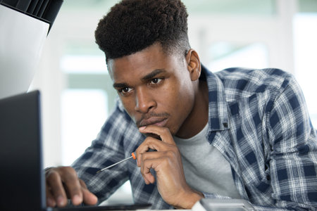 young concentrated guy repairing laptop