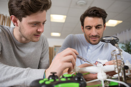 medium shot of a father and son repairing a drone