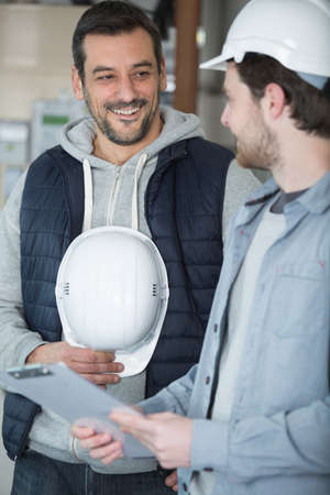 two workmen laughing and looking at clipboardの写真素材
