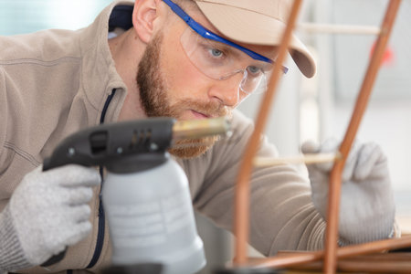 worker using blowtorch for soldering copper