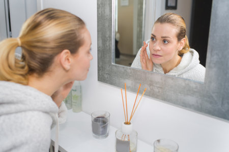 attractive girl putting anti-aging cream on her faceの写真素材