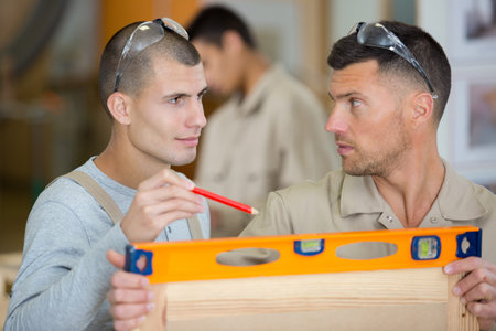 carpenters checking construction with spirit level