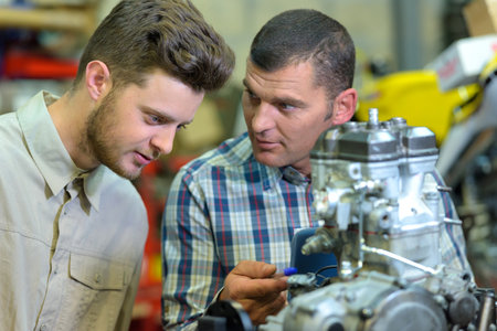 portrait of mechanics inspecting motorcycle motorの写真素材