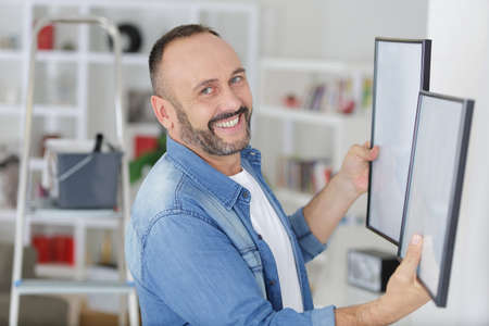 man is deciding where hanging the pictureの写真素材