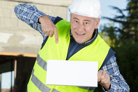 smiling worker pointing to a white placard