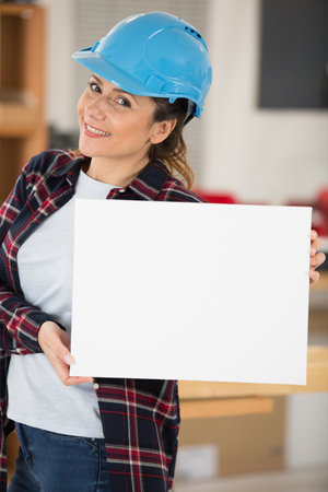 young woman construction worker holding a white boardの写真素材