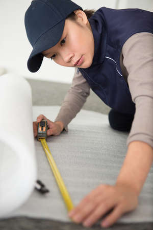 woman is measuring a piece of wallpaper rollsの写真素材