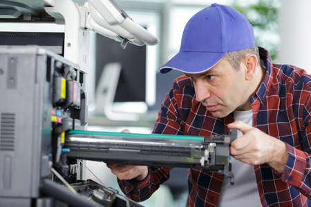 man changes the printer cartridge in the officeの写真素材