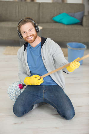 young domestic service man playing with mop a songの写真素材