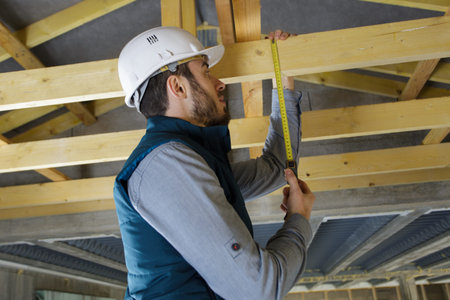worker measuring wood under roof prepare for ceiling installation
