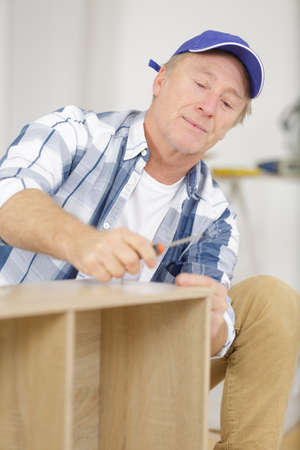casual mature man assembling furniture in new houseの写真素材