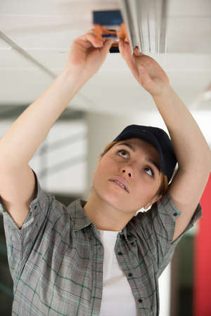 woman feeding cable above suspended ceilingの写真素材