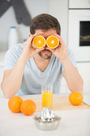 man holding orange halves over his eyesの写真素材