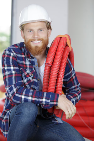 portrait of a contractor holding red electrical conduitの写真素材