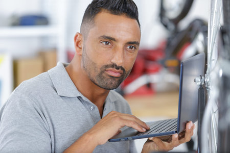 fixing a bike while looking at laptopの写真素材