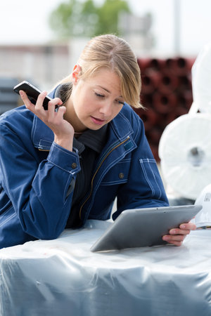 female worker in building materials yard using tablet