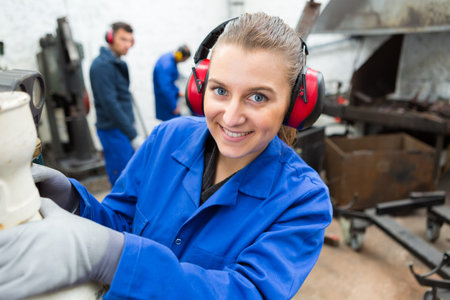 female worker wearing earmuffs in noisy workshopの写真素材