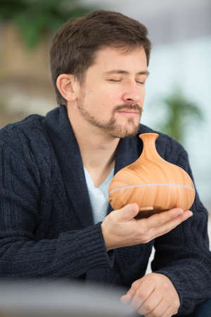man is smelling essential oil from an aroma diffuserの写真素材